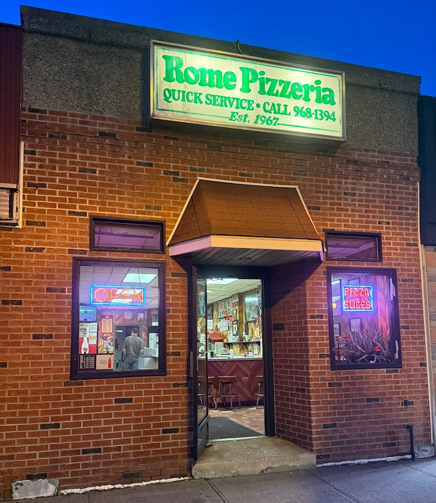 Rome Pizzeria storefront at night